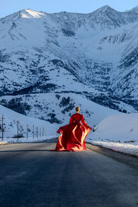 Rear view of woman walking on snow covered mountain