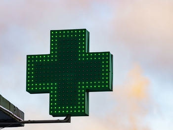 Low angle view of illuminated cross shape against sky in city