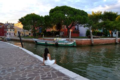 Young woman in front of building against sky