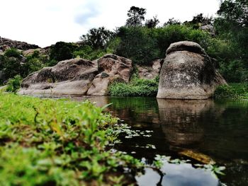 Scenic view of rock formation by trees against sky