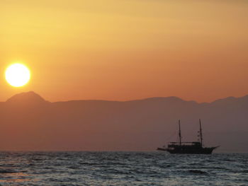 Silhouette sailboat in sea against sky during sunset