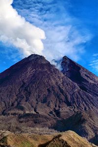 Scenic view of mt merapi steaming against blue sky