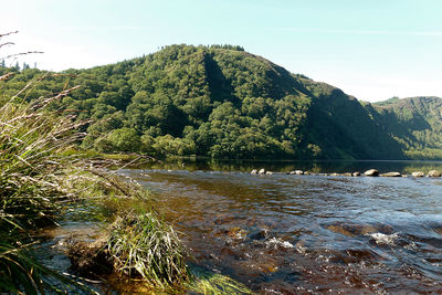 Scenic view of river by mountain against sky