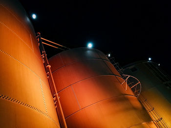 Low angle view of illuminated industry against sky at night
