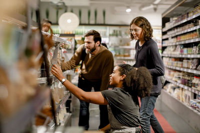 Side view of saleswoman assisting couple while working at supermarket