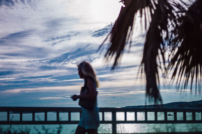 Side view of woman standing by sea against sky