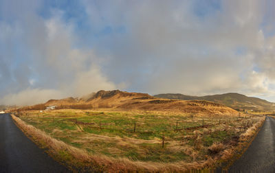 Road amidst field against sky