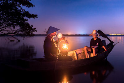 People fishing in lake at dusk