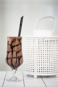 Drink in glass by basket on floor against white wall