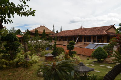 Houses and trees in garden against sky