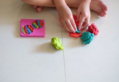 Low section of woman holding multi colored painting on table