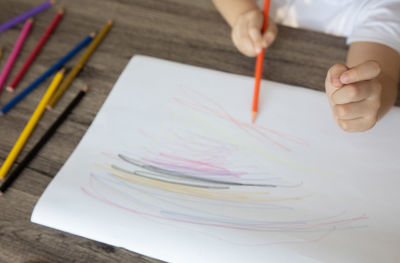 High angle view of hand holding paper on table