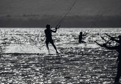 Silhouette people on sea against sky