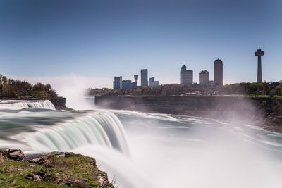 Long exposure of waterfall with city buildings seen in background
