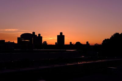 Silhouette buildings against orange sky