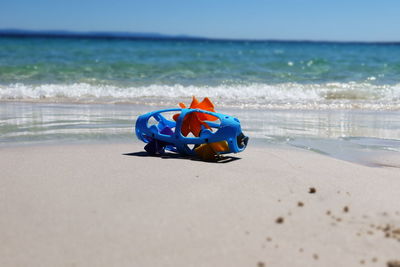 Toy on sand at beach against blue sky