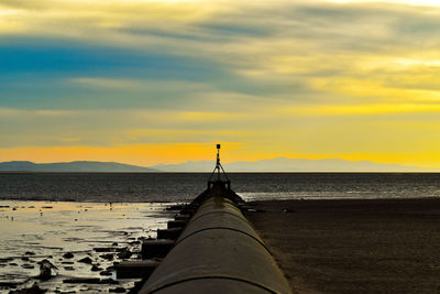 Surface level of yellow sea against sky during sunset