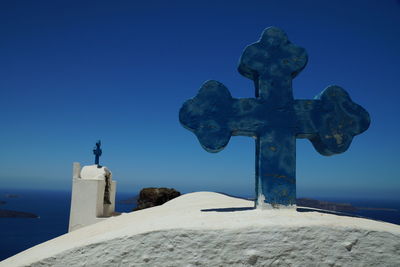 Close-up of cross sculpture against blue sky