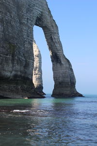 Rock formation in sea against clear sky