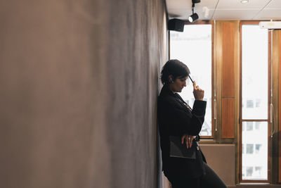 Side view of young woman looking through window
