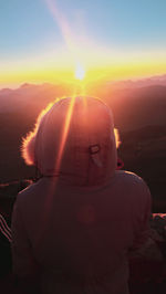 Rear view of woman against sky during sunset