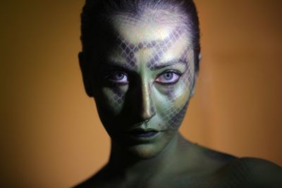 Portrait of young woman with face paint against colored background