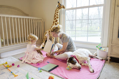 Mom and daughter read a book together while their dog sleeps