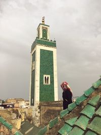 Side view of woman wearing hijab standing against mosque in city