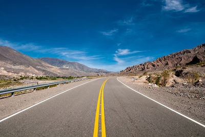 Road leading towards mountains against sky