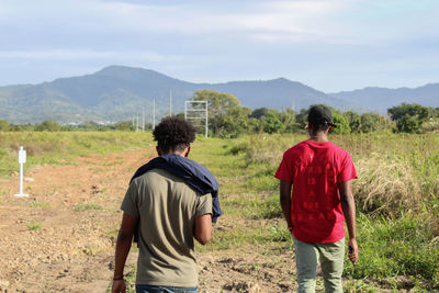 Rear view of people walking on landscape against sky