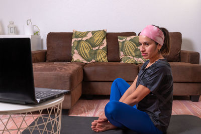Young woman using laptop while sitting on sofa at home