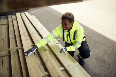 Smiling female worker arranging planks at lumber industry