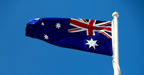 Low angle view of flag against blue sky