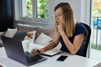 Woman working remotely from home office, using laptop
