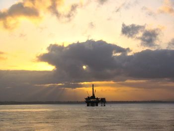 Silhouette ship in sea against sky during sunset