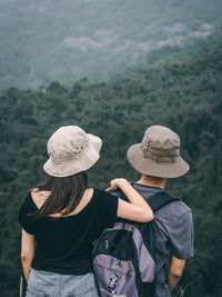 Rear view of man and woman standing on rock