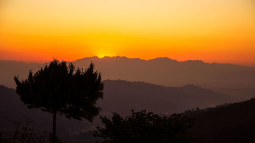 Silhouette trees on landscape against romantic sky at sunset