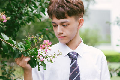 Low section of man holding flower against plants