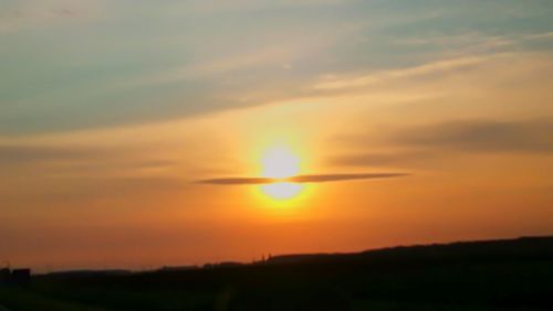 Scenic view of silhouette field against orange sky