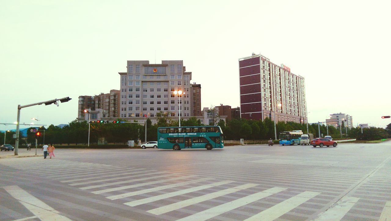 building exterior, architecture, built structure, city, clear sky, transportation, car, street, land vehicle, road, city life, skyscraper, copy space, modern, mode of transport, office building, city street, building, tall - high, incidental people