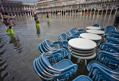Blue stacked chairs on water filled walkway during flood at piazza san marco