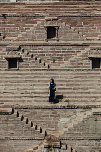 Woman on staircase against brick wall