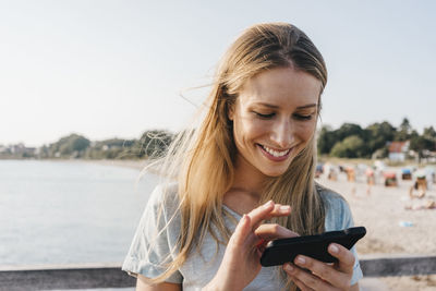 Smiling young woman using smartphone