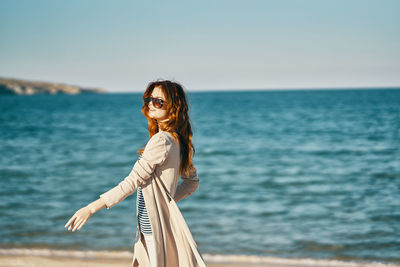 Woman standing by sea against sky