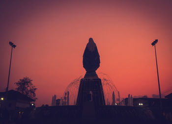 Silhouette statue against orange sky during sunset