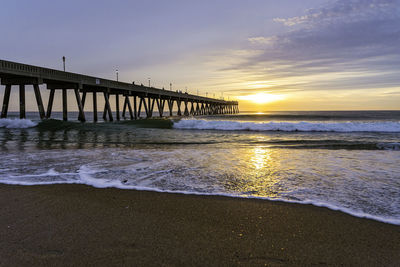 Pier over sea against sky during sunrise