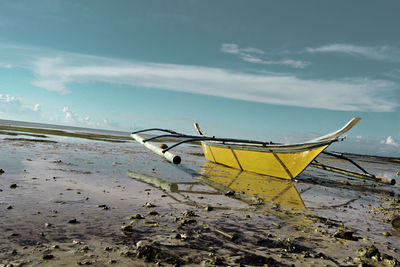 Fishing boat on beach against sky