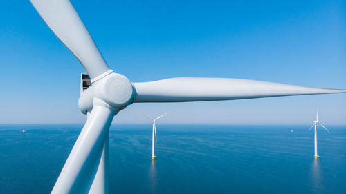 Low angle view of windmill against clear blue sky