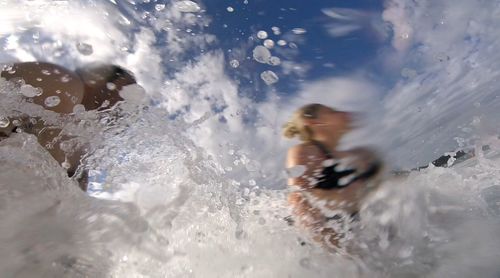 Low angle view of people enjoying in sea