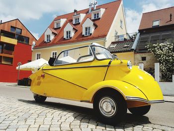 Yellow car on street against buildings in city